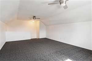 Additional living space with vaulted ceiling, dark carpet, and ceiling fan