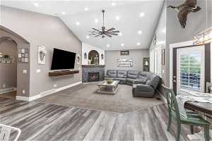 Living room featuring, high vaulted ceiling, ceiling fan, and a stone fireplace