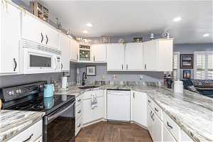 Kitchen featuring granite countertops, white cabinetry and included appliances