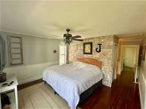 Bedroom with ceiling fan, crown molding, and dark wood-type flooring