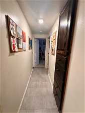 Hallway with a textured ceiling and light tile flooring