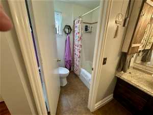 Full bathroom featuring shower / bathtub combination with curtain, toilet, tile floors, and vanity