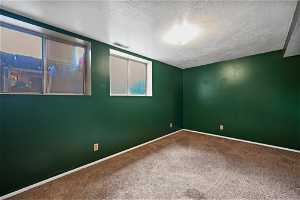 Unfurnished room featuring a textured ceiling and carpet
