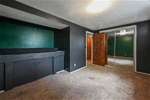 Unfurnished bedroom featuring a closet, a textured ceiling, and carpet flooring