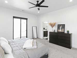 Bedroom featuring multiple windows, light carpet, ceiling fan, and ensuite bathroom