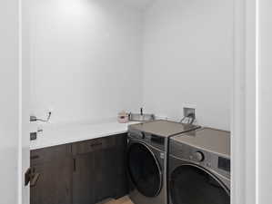 Clothes washing area with washer hookup, light hardwood / wood-style floors, cabinets, and washer and dryer