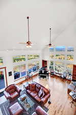 Living room with high vaulted ceiling, ceiling fan, and light hardwood / wood-style flooring