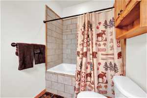 Bathroom with toilet and shower / tub combo with curtain