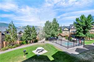 View of property's community with a hot tub, a patio area, a mountain view, and a yard
