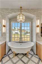 Bathroom with a bath to relax in, tile floors, and tile walls