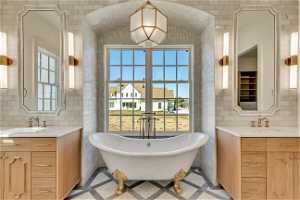 Bathroom with tile flooring, tile walls, and dual vanity