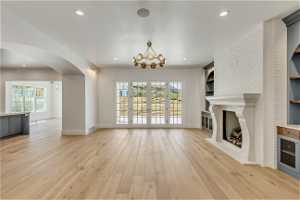 Unfurnished living room featuring light hardwood / wood-style flooring, a wealth of natural light, and a brick fireplace