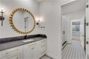 Bathroom with tile flooring, vanity, and a shower with door
