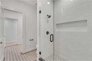 Bathroom with a shower with door, toilet, and tile floors