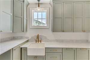 Kitchen featuring decorative light fixtures, sink, and light stone countertops