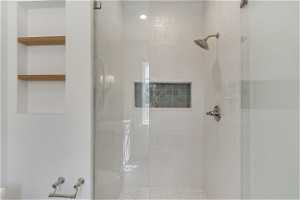 Bathroom featuring a shower with shower door, toilet, and built in shelves