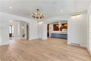 Unfurnished living room featuring light hardwood / wood-style flooring and a chandelier