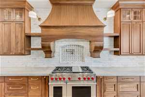Kitchen with backsplash, double oven range, and light stone counters