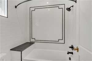 Bathroom with tiled shower / bath, toilet, and tile walls