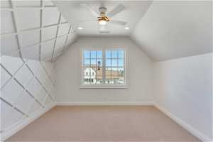Additional living space featuring light colored carpet, vaulted ceiling, and ceiling fan
