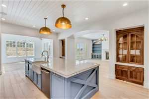 Kitchen with light hardwood / wood-style flooring, dishwasher, a kitchen island with sink, sink, and pendant lighting