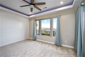 Unfurnished room with light carpet, ceiling fan, and a raised ceiling