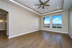 Unfurnished room featuring ceiling fan, a raised ceiling, and dark hardwood / wood-style floors