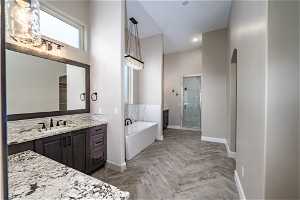 Bathroom featuring separate shower and tub, vanity, and parquet flooring