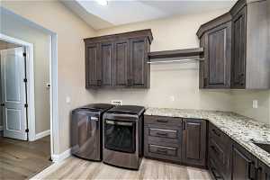 Washroom with light hardwood / wood-style flooring, cabinets, hookup for a washing machine, and washer and dryer