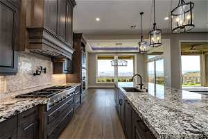 Kitchen with dark brown cabinetry, sink, pendant lighting, and light hardwood / wood-style floors
