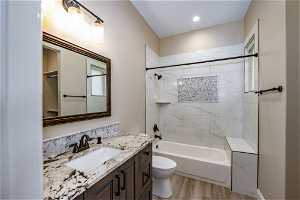 Full bathroom with tiled shower / bath, hardwood / wood-style flooring, toilet, and vanity