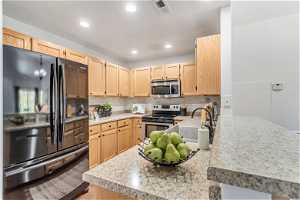 Kitchen featuring light brown cabinetry, tasteful backsplash, black appliances with stainless steel finishes, and sink