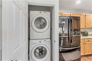 Laundry room with light wood-type flooring and stacked washer / drying machine