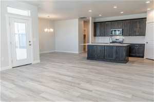 Kitchen with dark brown cabinetry, light hardwood / wood-style floors, backsplash, stove, and pendant lighting