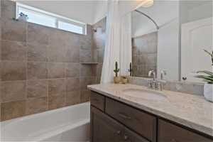 Bathroom featuring shower / bathtub combination with curtain and vanity
