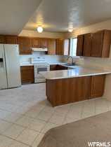 Kitchen featuring sink, tan fridge, and tan stove. kitchen peninsula, and light tile flooring