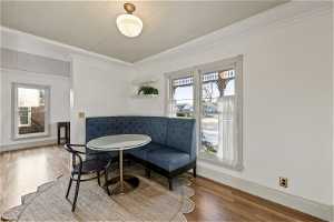 Sitting room with plenty of natural light, light wood-type flooring, and ornamental molding