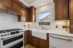 Kitchen featuring sink, double oven range, white subway tile backsplash, and light wood-type flooring