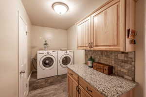 Laundry room featuring washer and clothes dryer, dark hardwood / wood-style flooring, and cabinets