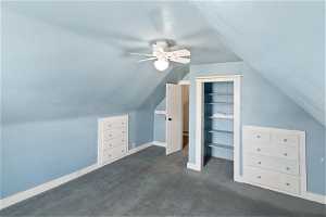 Bedroom featuring vaulted ceiling, dark carpet, ceiling fan, and built-in features