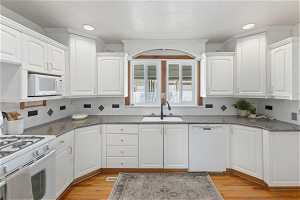 Kitchen featuring white cabinets, sink, light hardwood / wood-style floors, and white appliances