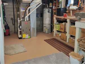 Utilities area with high efficiency furnace, strapped water heater, and workbench