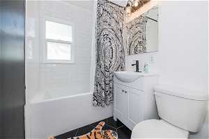 Full bathroom with toilet, tile floors, vanity, and shower / bath combination with curtain
