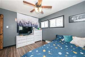 Bedroom with dark hardwood / wood-style flooring, ceiling fan, and a baseboard radiator