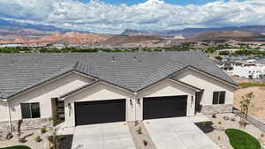 Ranch-style house featuring concrete driveway, an attached garage, a mountain view, and stucco siding