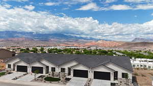 Ranch-style house featuring a mountain view, concrete driveway, stucco siding, and a garage