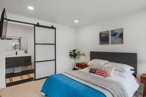 Carpeted bedroom featuring a barn door and ensuite bathroom