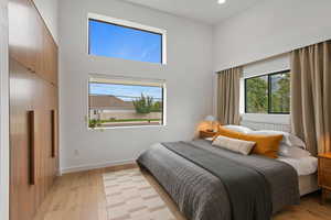 Bedroom with a high ceiling and light hardwood / wood-style flooring