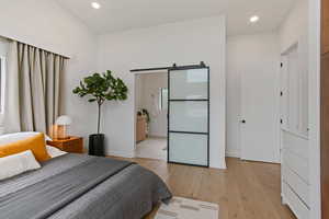 Bedroom featuring a barn door and light hardwood / wood-style flooring