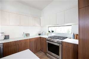 Kitchen with light hardwood / wood-style flooring, stainless steel appliances, and white cabinets